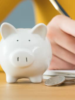 Geld sparen - vrouw houdt haar budget bij in een notitieboekje. Geld sparen - vrouw houdt haar budget bij in een notitieboekje.