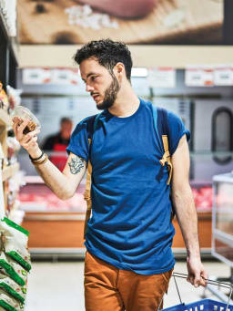 Goedkoop winkelen: Man vergelijkt prijzen in de supermarkt. Goedkoop winkelen: Man vergelijkt prijzen in de supermarkt.