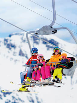 Winterurlaub mit Kindern: Familie fährt mit einem Skilift den Berg hinauf. Winterurlaub mit Kindern: Familie fährt mit einem Skilift den Berg hinauf.