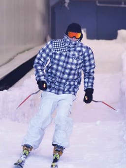 Skihalle: Ein Skifahrer fährt eine Indoor-Skipiste herunter. Skihalle: Ein Skifahrer fährt eine Indoor-Skipiste herunter.