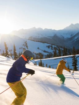 Schönste Skigebiete: Skifahrer fahren im Sonnenschein einen schneebedeckten Hang herunter. Schönste Skigebiete: Skifahrer fahren im Sonnenschein einen schneebedeckten Hang herunter.