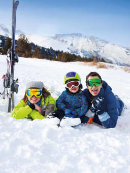 Skifahren Regeln: Familie liegt im Schnee und lacht in die Kamera. Skifahren Regeln: Familie liegt im Schnee und lacht in die Kamera.