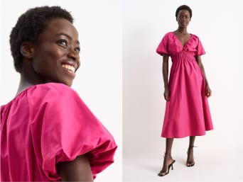 Woman in a floor-length purple A-line dress walks down the street in high heels | C&A Woman in a floor-length purple A-line dress walks down the street in high heels | C&A