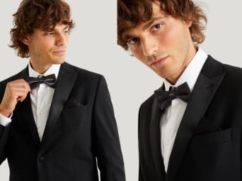 Tying a bow tie: a man wearing a black suit with a matching bow tie. Tying a bow tie: a man wearing a black suit with a matching bow tie.