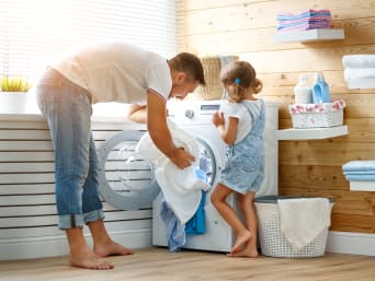 Washing shirts: a dad with his daughter putting shirts into a washing machine.  Washing shirts: a dad with his daughter putting shirts into a washing machine.