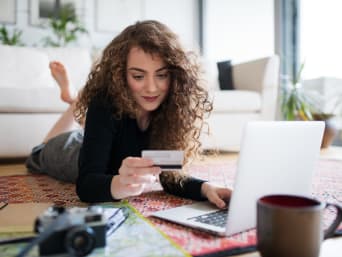 Een jaar in het buitenland financieren - scholiere boekt haar reis met haar creditcard op haar laptop.