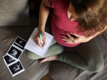 Schwangere Frau schreibt Namensideen für ihr Baby in ein Notizbuch. Schwangere Frau schreibt Namensideen für ihr Baby in ein Notizbuch.