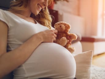 Schwangere Frau hält einen Teddybären gegen ihren Babybauch. Schwangere Frau hält einen Teddybären gegen ihren Babybauch.
