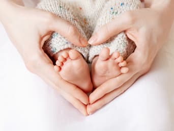Hände umfassen kleine Babyfüße und formen dabei ein Herz. Hände umfassen kleine Babyfüße und formen dabei ein Herz.
