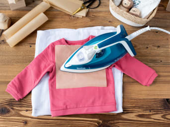 Mit Bügelfolie, Backpapier und Bügeleisen kannst du die Schrift auf den Pullover bringen. Mit Bügelfolie, Backpapier und Bügeleisen kannst du die Schrift auf den Pullover bringen.