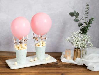 Selbstgebastelte Deko-Heißluftballons gefüllt mit Popcorn als süße Babyparty-Tischdeko. Selbstgebastelte Deko-Heißluftballons gefüllt mit Popcorn als süße Babyparty-Tischdeko.
