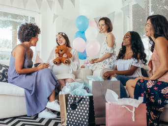 Werdende Mama packt die Babyparty-Geschenke mit ihren Gästen aus. Werdende Mama packt die Babyparty-Geschenke mit ihren Gästen aus.