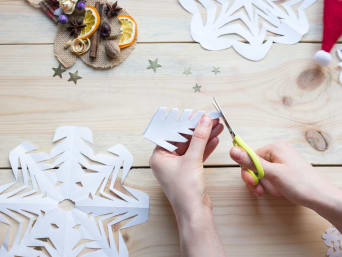 Schneeflocken basteln – Kind bastelt Schneeflocken aus Papier. Schneeflocken basteln – Kind bastelt Schneeflocken aus Papier.