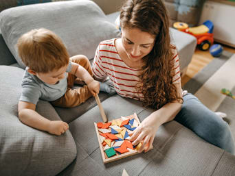 Nachhaltiges Spielzeug – Mutter und Sohn spielen mit einem Holz-Puzzle. Nachhaltiges Spielzeug – Mutter und Sohn spielen mit einem Holz-Puzzle.