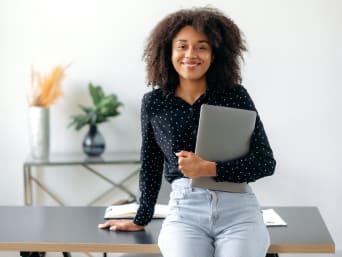 Schülerpraktikum: Teenager lehnt an einem Tisch und hält einen Laptop in der Hand. Schülerpraktikum: Teenager lehnt an einem Tisch und hält einen Laptop in der Hand.