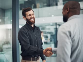 Business Kleidung – Mann im Business Casual Look wird von Personaler begrüßt. Business Kleidung – Mann im Business Casual Look wird von Personaler begrüßt.