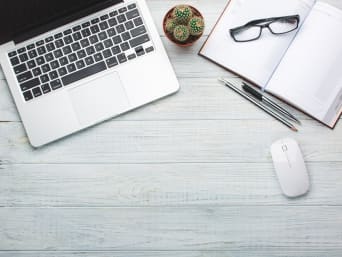 Ergonomie am Arbeitsplatz: Laptop und Notizbuch liegen auf einem Tisch. Ergonomie am Arbeitsplatz: Laptop und Notizbuch liegen auf einem Tisch.