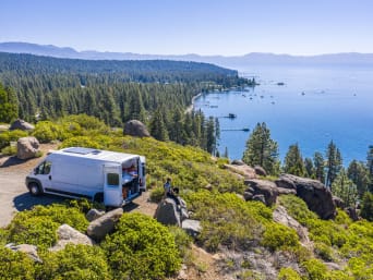 Green Camping: Wohnmobil steht im Grünen auf einer Anhöhe in der Nähe eines Sees.
