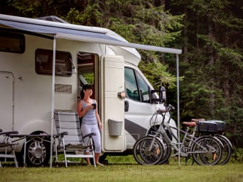 Groen kamperen − jonge vrouw drinkt thee voor de camper. Groen kamperen − jonge vrouw drinkt thee voor de camper.