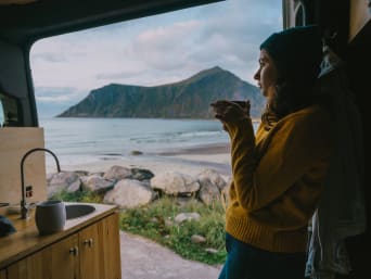 Green Camping: Junge Frau trinkt einen Tee in ihrem Wohnmobil.