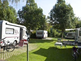 Campingregels − geparkeerde caravans en campers met campingmeubels en fietsen. Campingregels − geparkeerde caravans en campers met campingmeubels en fietsen.