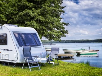 Camping regels: caravan staat met campingmeubels aan een meer. Camping regels: caravan staat met campingmeubels aan een meer.