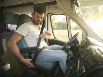Sicherer Campingurlaub: Fahrer schnallt sich im Wohnmobil an.