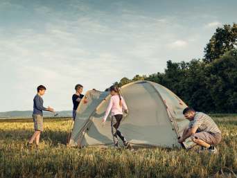 Kamperen met kinderen – een familie zet een tent op.