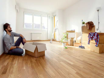 Mann ruht sich während des Einzugs in der neuen Wohnung aus. Mann ruht sich während des Einzugs in der neuen Wohnung aus.