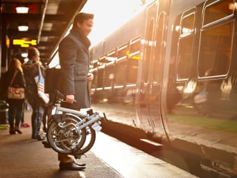 Mann nutzt den Zug und sein Faltrad, um zur Arbeit zu pendeln. Mann nutzt den Zug und sein Faltrad, um zur Arbeit zu pendeln.