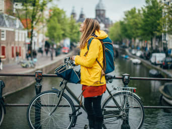 Regenbekleidung Fahrrad: Frau schützt sich mit einer Regenjacke vor Nässe beim Radfahren. Regenbekleidung Fahrrad: Frau schützt sich mit einer Regenjacke vor Nässe beim Radfahren.