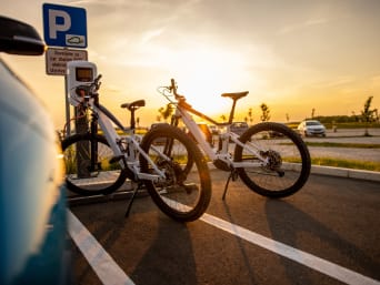 E-Bike laden: Elektrofahrräder stehen auf einem Parkplatz an einer Ladesäule. E-Bike laden: Elektrofahrräder stehen auf einem Parkplatz an einer Ladesäule.