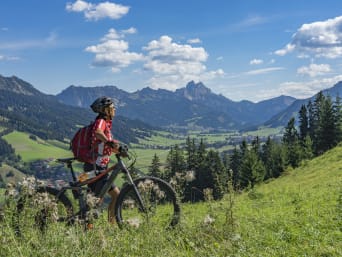 Radtouren Tirol: Eine Frau steht mit einem Fahrrad auf einer Wiese in Tirol. Radtouren Tirol: Eine Frau steht mit einem Fahrrad auf einer Wiese in Tirol.