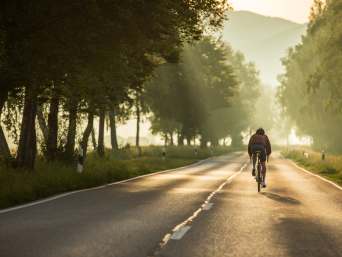 Wegwielrennen: een man fietst op zijn racefiets over een verharde weg.