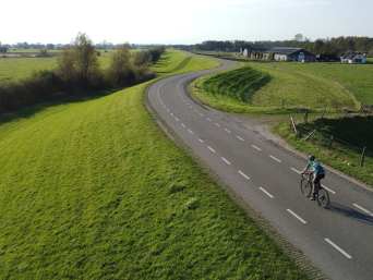 Wielersport regels: een man fietst over een dijk met zijn racefiets.