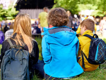 Het festival met kinderen meemaken: groep kinderen zit aan de rand van het evenemententerrein. Het festival met kinderen meemaken: groep kinderen zit aan de rand van het evenemententerrein.