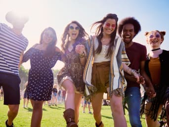 Festival outfit voor dames: Vrienden in zomerse festivaloutfits lopen over het festivalterrein. Festival outfit voor dames: Vrienden in zomerse festivaloutfits lopen over het festivalterrein.