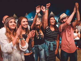 Festival outfit voor dames: Festivalbezoekers in stijlvolle festivallooks juichen een band toe. Festival outfit voor dames: Festivalbezoekers in stijlvolle festivallooks juichen een band toe.