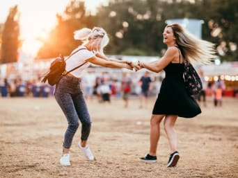 Sportieve festival outfit: vriendinnen dansen op het festivalterrein. Sportieve festival outfit: vriendinnen dansen op het festivalterrein.