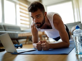 Online fitness: young man doing a plank with guidance from a fitness video. Online fitness: young man doing a plank with guidance from a fitness video.