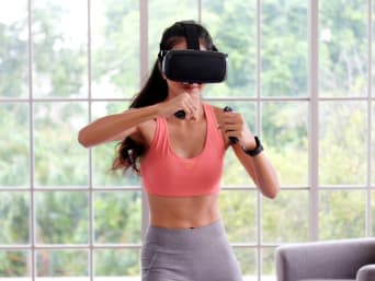 Young woman wearing VR-goggles for training with a fitness game. Young woman wearing VR-goggles for training with a fitness game.
