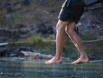 Slackline – man is balancing on a slackline above the water. Slackline – man is balancing on a slackline above the water.