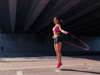 Rope skipping – woman skipping using a pink rubber skipping rope. Rope skipping – woman skipping using a pink rubber skipping rope.