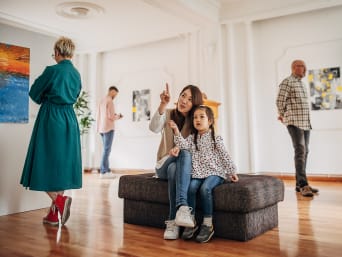 Museum voor kinderen – Moeder en dochter kijken zittend naar kunst. Museum voor kinderen – Moeder en dochter kijken zittend naar kunst.