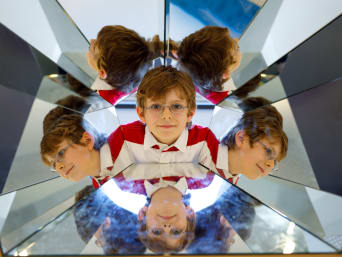 Met kinderen naar het museum - jongen kijkt in een doos met spiegels.
