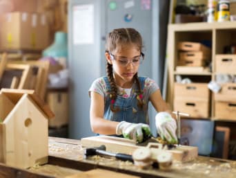 Knutselen voor kinderen: meisje maakt houtwerk in een houtwerkplaats. Knutselen voor kinderen: meisje maakt houtwerk in een houtwerkplaats.