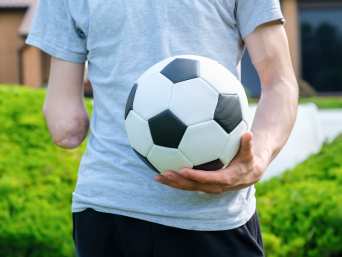 Inklusion Fussball: Eine Person mit Armamputation hält einen Fussball. Inklusion Fussball: Eine Person mit Armamputation hält einen Fussball.