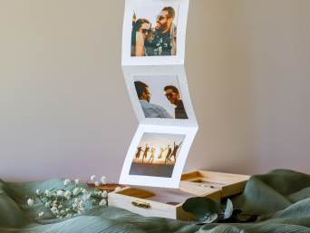Geschenkideen für die beste Freundin: Eine Fotobox mit gemeinsamen Fotos von Freunden liegt auf einem Tisch.
