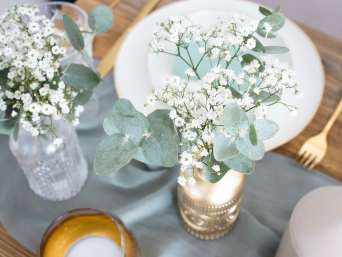 Tischdeko Goldene Hochzeit Blumen – Eukalyptus und Schleierkraut in einer goldenen Vase.