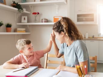 Huiswerkmotivatie - moeder en zoon geven een high-five na het huiswerk. Huiswerkmotivatie - moeder en zoon geven een high-five na het huiswerk.
